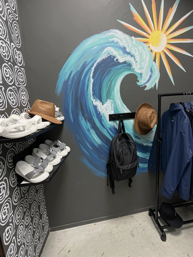 Interior de loja de surf com prateleiras de madeira, pranchas coloridas expostas na parede e iluminação pendente.